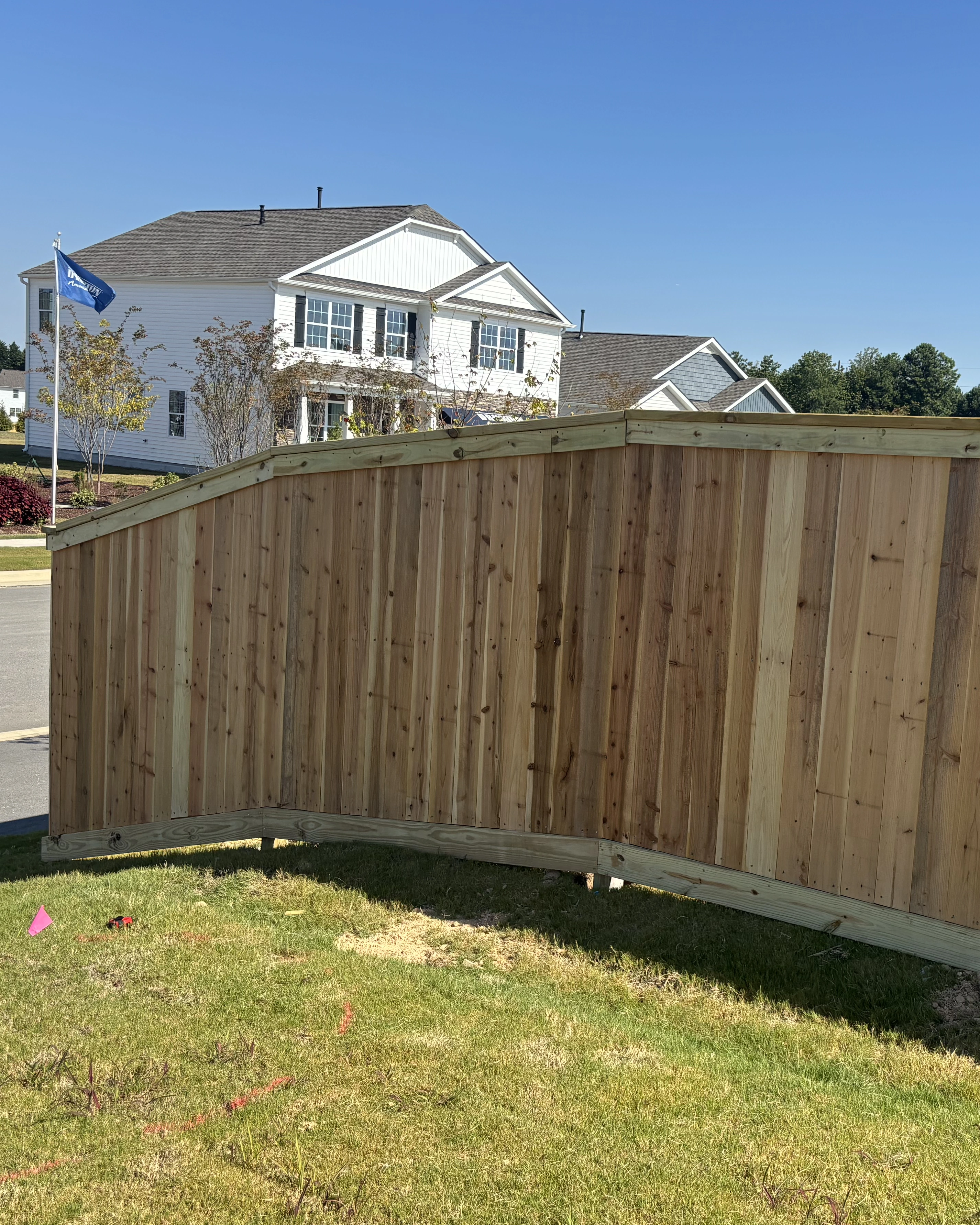 Curved cedar privacy fence installed along a neighborhood street with a smooth arched top rail.