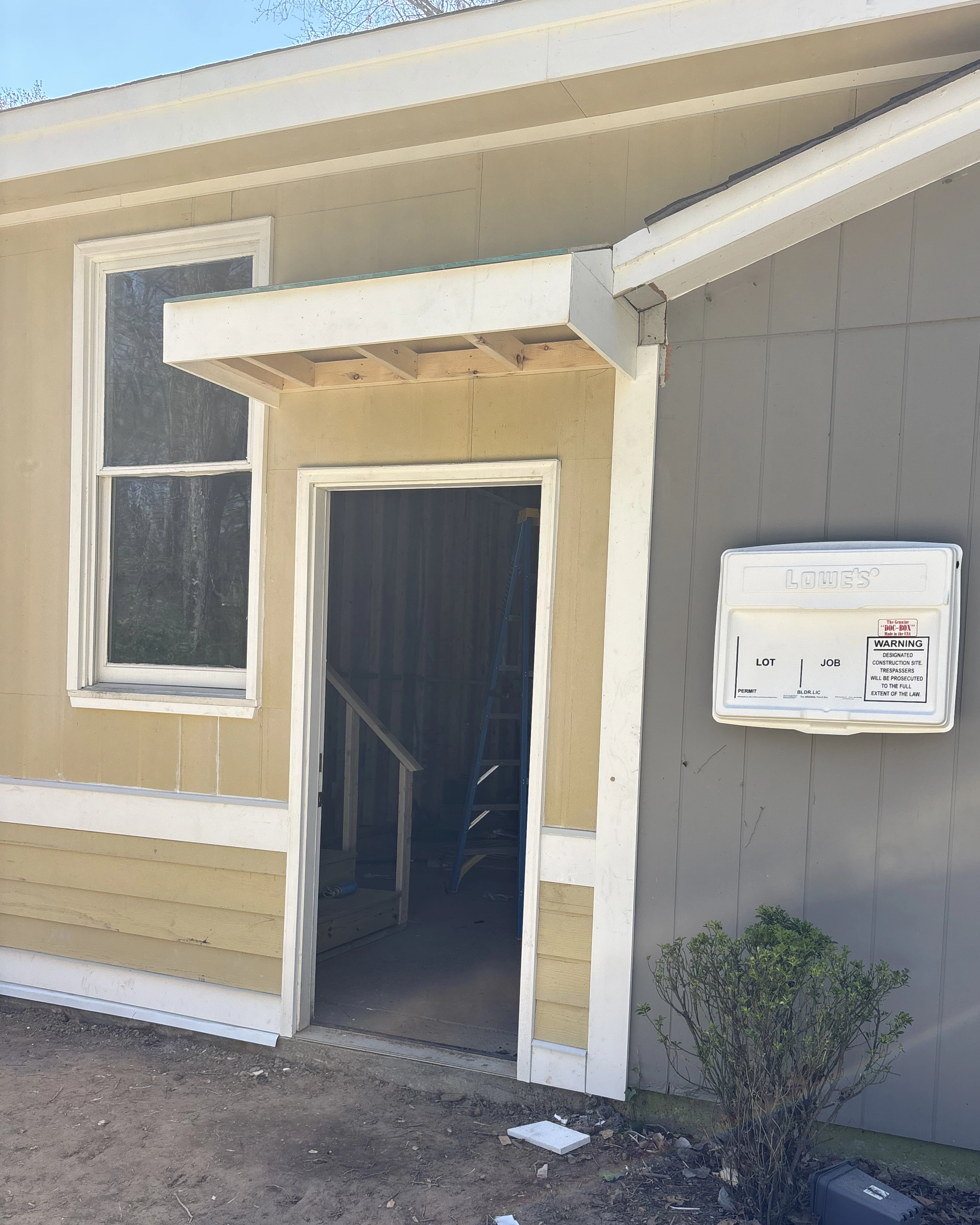 Framing for a small exterior entry awning being built above a side door.