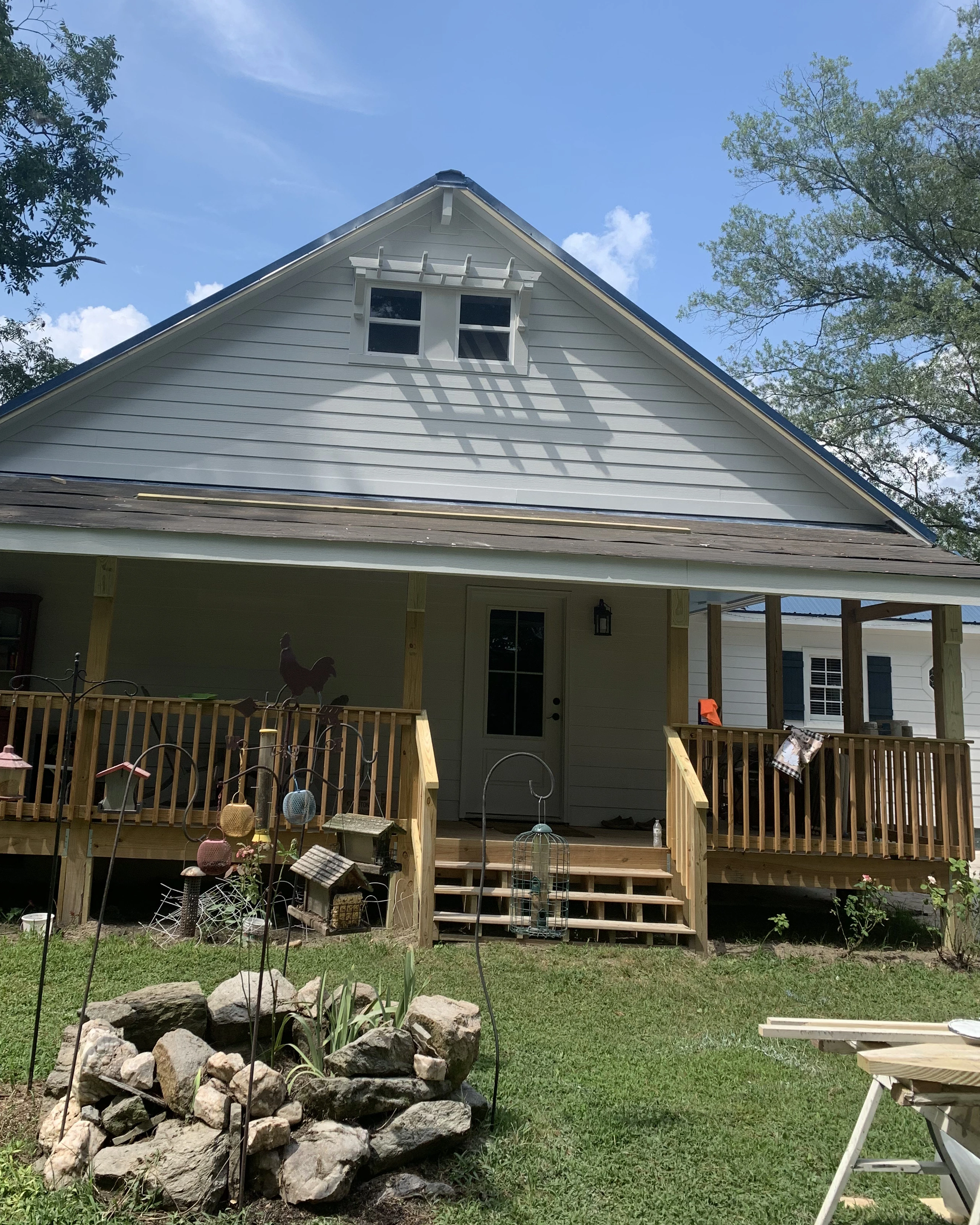 Front porch rebuild with new decking, stairs, and structural posts on a farmhouse-style home.