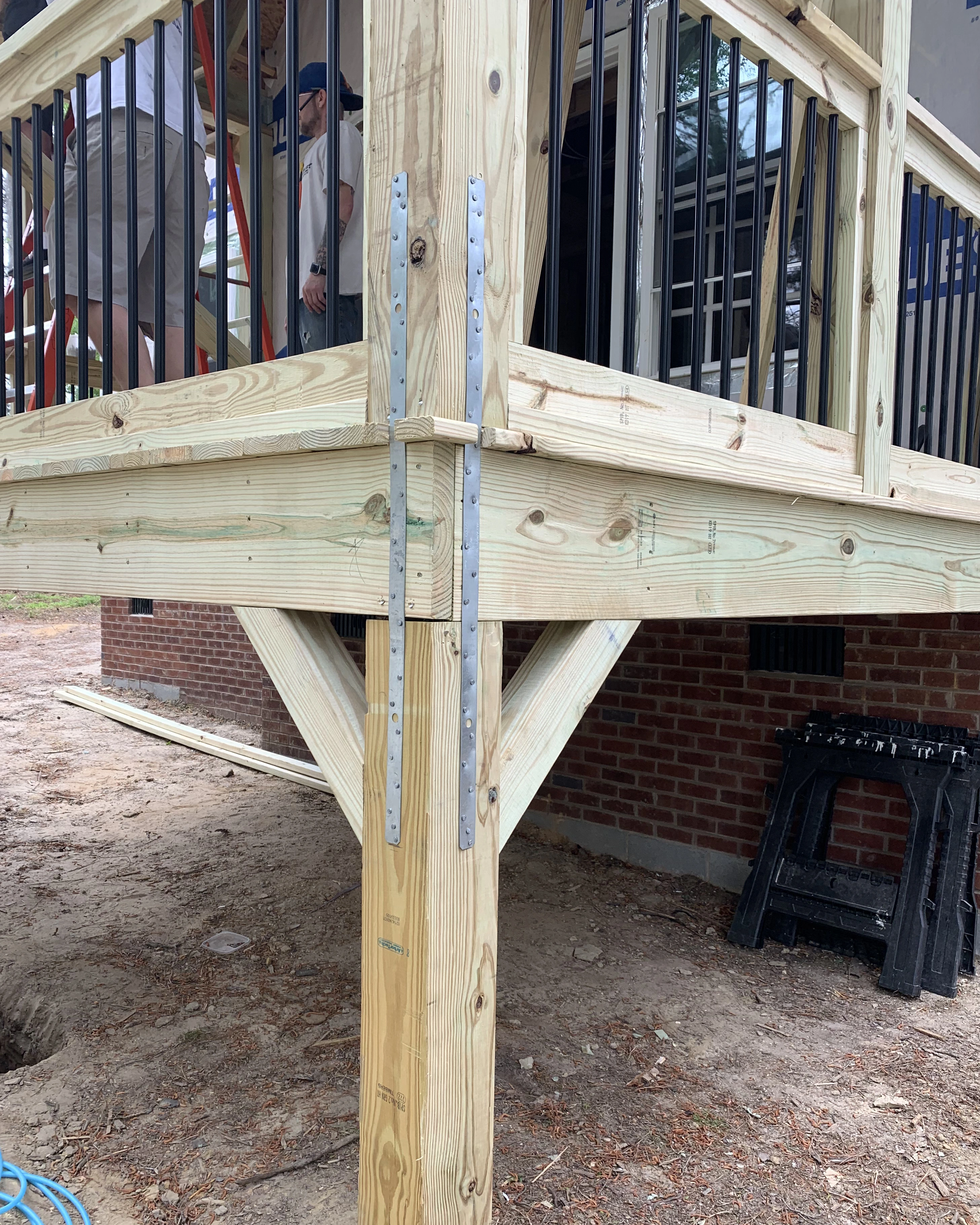 Corner post bracing with metal straps on a raised wood deck.
