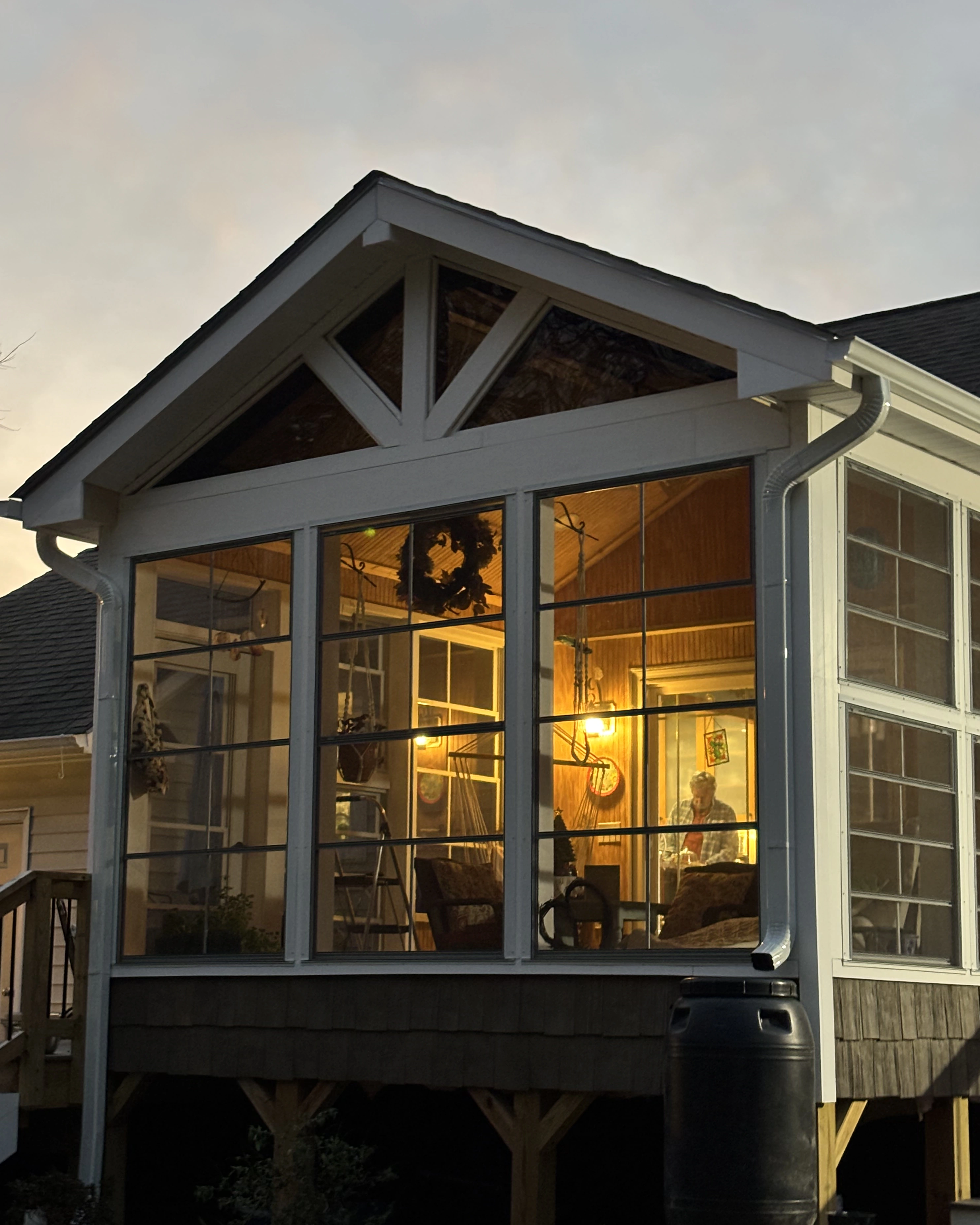 Sunroom exterior at dusk glowing with warm interior lighting.
