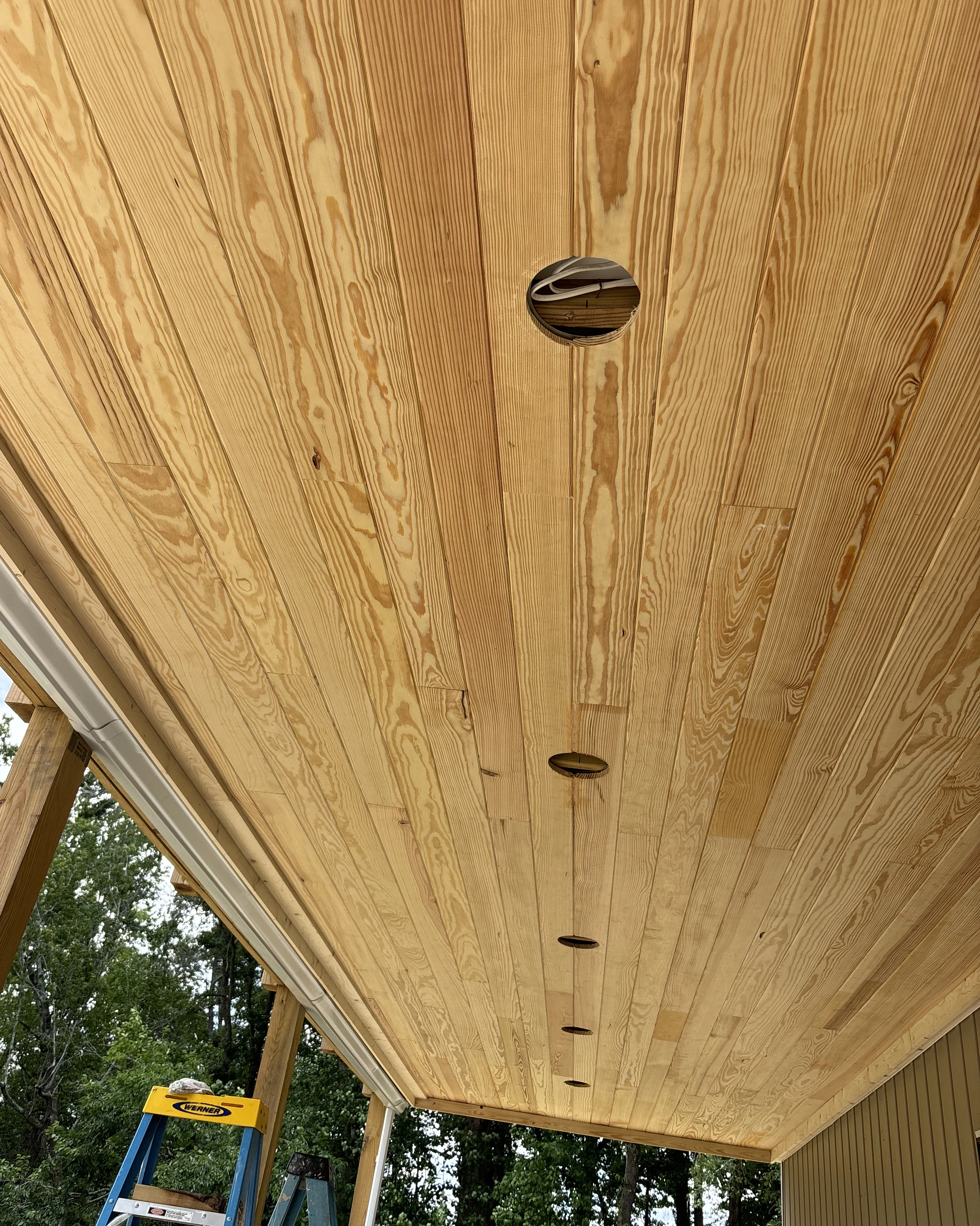 Tongue-and-groove wood ceiling with recessed light cutouts.